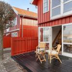 Red wooden house with terrace, two chairs, and table. Glass doors lead to interior.