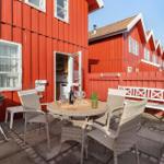 Red wooden house with terrace, grill, and seating. Backyard with white benches.