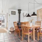 Dining room with wooden table, chairs, and wood stove. Kitchen on left. Wall map and deer antlers.
