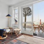 Room with seating and view to terrace with garden furniture and harbor view.