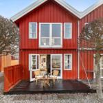 Red wooden house with terrace and garden. Windows and doors are white.