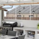 Terrasse mit Grill, Waschbecken und Hängelampen unter einer Markise.