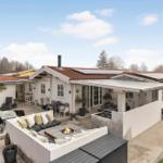 Haus mit Terrasse, Sitzgelegenheiten und Feuerkorb im Freien.