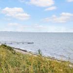 Strand mit Steg und Brücke im Hintergrund unter blauem Himmel