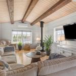 Wohnzimmer mit Holzdecke, Sofa, Fernseher und Kaminofen.