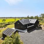 Moderne schwarze Hütte mit Garten und Blick auf grüne Felder.