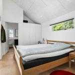 Schlafzimmer mit Bett, Schrank und Fenster. Badezimmer im Hintergrund.