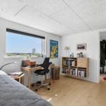 Schlafzimmer mit Schreibtisch, Bücherregal und Blick auf die Landschaft.