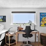 Zimmer mit Bett, Schreibtisch, Stuhl und Fenster mit Blick auf Landschaft.