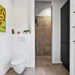 Badezimmer mit Toilette, Dusche und Wandbild.