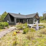 Moderne Villa mit großem Garten und Terrasse. Holz- und Glasfassade. Grünflächen und Bäume umgeben das Haus.