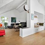 Wohnraum mit rotem Sessel, schwarzer Couch und Holzboden.