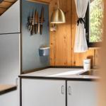 Küche mit Holzwand, Fenster, Küchenzeile und Hängeschneidemaschine.