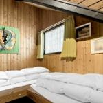 Zwei Betten mit weißen Laken in einem Holzhaus mit Fenster und Wanddekoration.