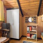 Zimmer mit Holzwand, Doppelbett, Schrank, Bücherregal und Fenster mit gelben Vorhängen.