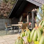 Terrasse mit Tisch und Stühlen vor einem Holzhaus mit Glasfront.