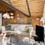 Wohnzimmer mit Holzwand, Sofa, Fernseher und Glas-Tisch.