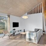 Living room with wooden ceiling, sofa, TV, and large window to nature.