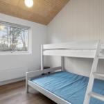 Room with bunk bed, wooden floor, and window with forest view.
