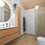Bathroom with sink, shower, and toilet. Wood and stone look.