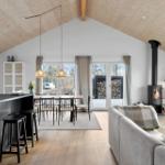Living and dining area with fireplace, large windows, and wooden ceiling.