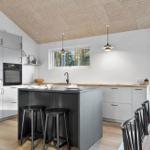 Modern kitchen with island, wooden ceiling, and view of the garden.