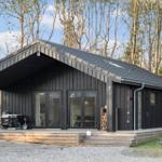Modern black cabin with wooden terrace and grill in the woods