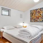 Schlafzimmer mit Bett, Nachttisch und Wandbild.