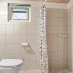 Badezimmer mit Toilette, Dusche und kleinem Fenster.