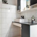 Badezimmer mit Waschbecken, Schrank und Handtuchhalter an Wand.