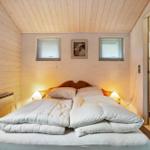Schlafzimmer mit Bett, zwei Fenstern und angrenzender Toilette.