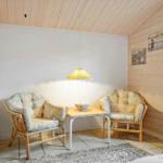 Zwei Stühle und ein Tisch unter einer Lampe in einem Raum mit Holzwand und -decke.