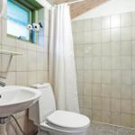 Badezimmer mit Dusche, Toilette und Waschbecken mit Spiegel.