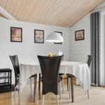 Esszimmer mit runden Tisch, schwarzen Stühlen und Holzdecke. Durchgang zur Außenterrasse.
