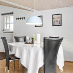 Esszimmer mit runden Tisch, schwarzen Stühlen und weißen Bildern an der Wand.