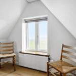 Room with two wooden chairs, window, and radiator.