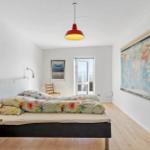 Bedroom with bed, world map, and ceiling lamp.