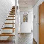 Hallway with wooden staircase, mirror, and wooden door.