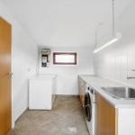 Laundry room with washing machine, sink, and small window.