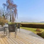 Deck with table and chairs, view of green fields and trees.