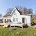 White house with terrace and garden. Wooden terrace with table and chairs.
