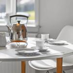 Table with cups, saucers, and kettle by window
