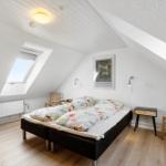 Bedroom with skylight, bed, chairs, and bedside table.