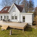 House with wooden terrace and garden. Outdoor seating area.