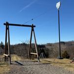Zugang zum Seilpark mit Holzgerüst und Blick auf bewaldete Hügel.