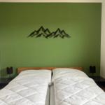 Schlafzimmer mit grüner Wand und Berg-Dekoration über dem Bett.