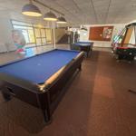 Raum mit zwei Billardtischen und einem Air-Hockey-Spielplatz.