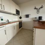 Küche mit weißen Schränken, Holzoberfläche und Wanddekoration