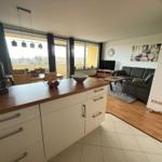 Küche mit Essbereich und Wohnzimmer mit Sofa und Balkon.