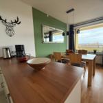 Küche mit Essbereich und Balkonansicht. Wanddekoration und Holzmöbel.